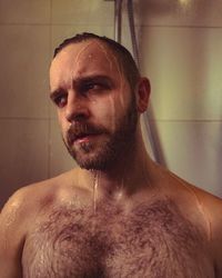 Shirtless mid adult man taking shower in bathroom