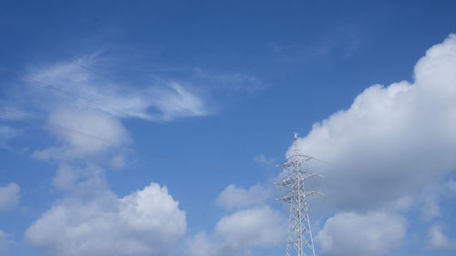 Low angle view of electricity pylon against blue sky