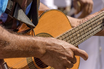 Detail of guitarist's hands and his acoustic guitar at an outdoor popular music presentation