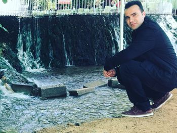 Portrait of young man against waterfall