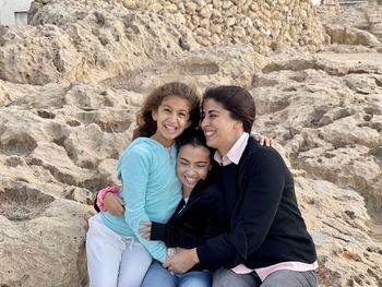 Portrait of mother with two young girls daughters sitting near the beach sea