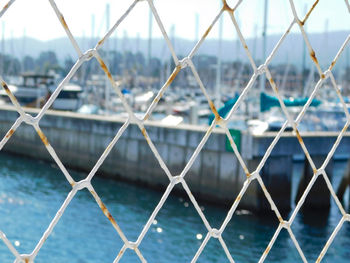 Close-up of chainlink fence against sea