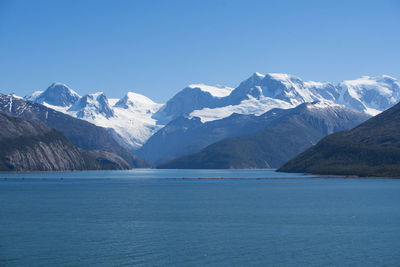 Scenic view of snowcapped mountains and sea against blue sky