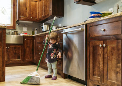 Girl cleaning kitchen with mop at home