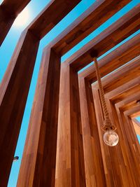 Low angle view of light bulb hanging from wooden ceiling