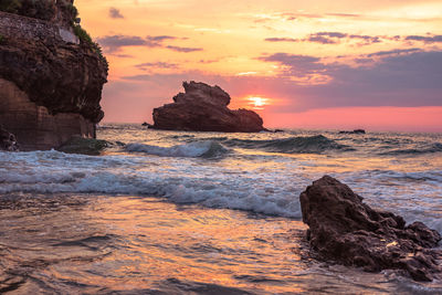 Rock formation on sea against sky during sunset