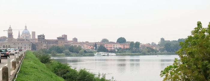 View of buildings by river against clear sky