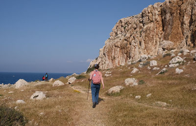 Man standing on rock by sea against sky