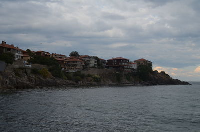 Buildings in town against cloudy sky