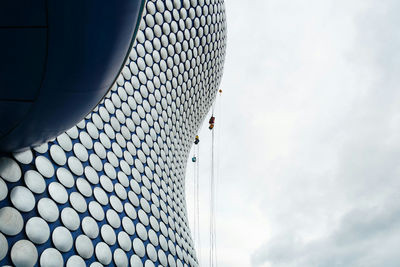 Low angle view of modern building against cloudy sky