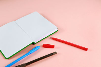 Close-up of diary and pens on pink background