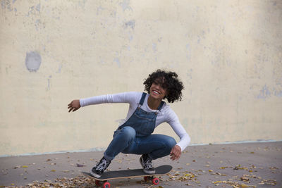 Full length of woman smiling while standing against wall