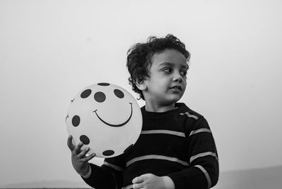 Portrait of girl playing with balloons against wall