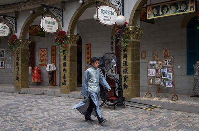 Woman walking on street against buildings in city