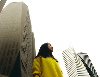 Low angle view of woman standing against modern buildings