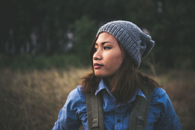 Close-up of thoughtful young woman wearing knit hat while standing on field