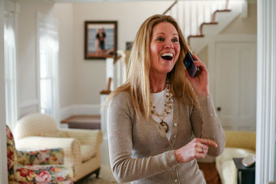 Happy woman talking on phone in living room at home