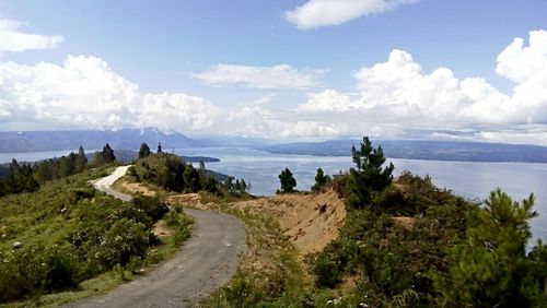 Empty road and lake against sky