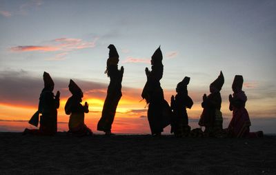 Silhouette people on beach against sky during sunset