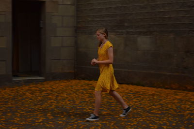 Full length of woman standing against yellow wall