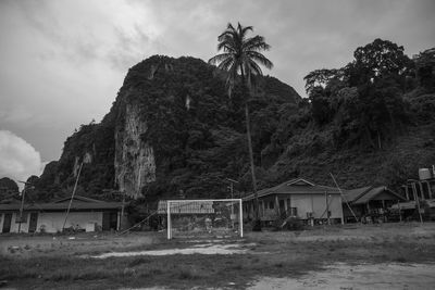 House by palm trees on field against sky