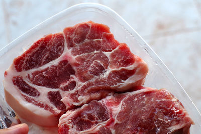High angle view of raw pork in plastic container