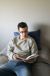 Young man lying on bed reading a book