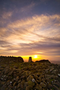 Rocks on land against sky during sunset