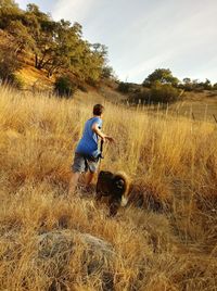 Rear view of boy with dog running on field