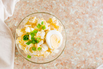 Homemade potato salad with egg and green onions in a bowl on the table. top view. close-up