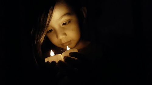 Close-up of girl holding illuminated light in darkroom