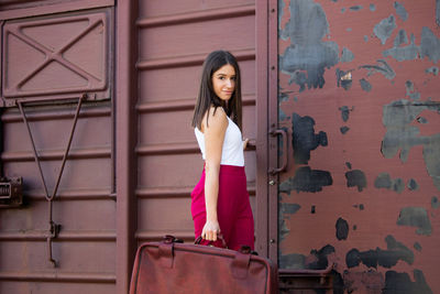 Portrait of woman standing against brick wall