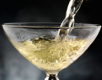 Close-up of wineglass on glass against white background