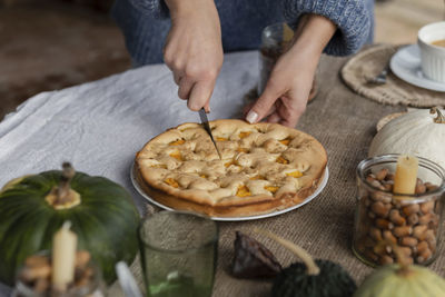 Hands of woman cutting homemade pumpkin pie