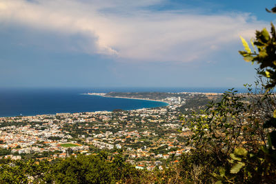Aerial view of townscape by sea against sky