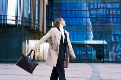 Successful happy business woman with bag over office building background person