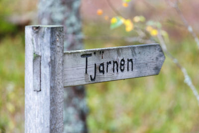 Close-up of sign on wooden post