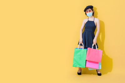 Full length of a beautiful young woman against yellow background