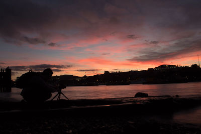 Silhouette man photographing at sunset