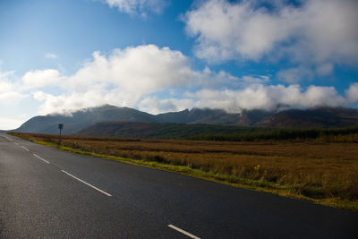 Road by mountains against sky