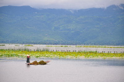 Man on riverbank against sky