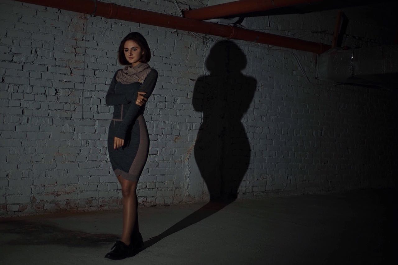 FULL LENGTH PORTRAIT OF YOUNG WOMAN STANDING AGAINST BRICK WALL