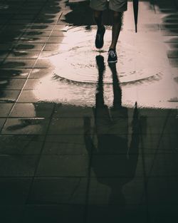 Low section of man standing on wet street