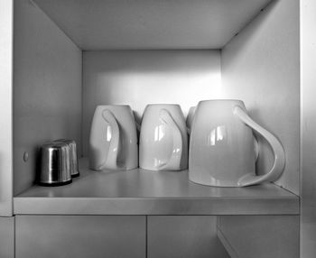 Close-up of mugs in cabinet