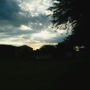 Silhouette of house against cloudy sky