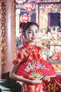 Young woman with red umbrella standing in traditional clothing