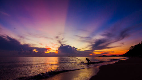 Scenic view of sea against dramatic sky during sunset