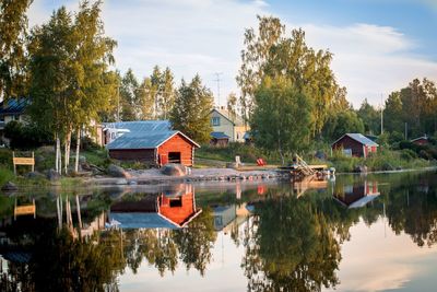 Houses by lake and buildings against sky