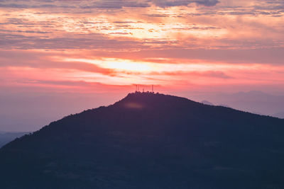 Scenic view of silhouette mountains against orange sky