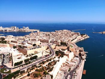Aerial view of townscape by sea against clear sky during sunny day